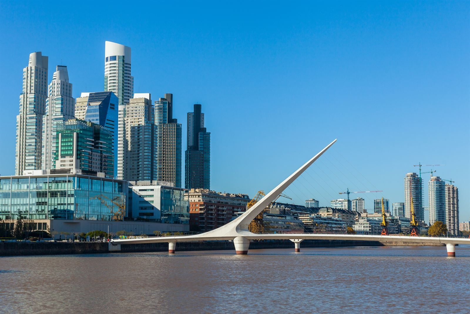 White Puente de la Mujer footbridge over the water in Puerto Madero, Buenos Aires, with glass towers behind
