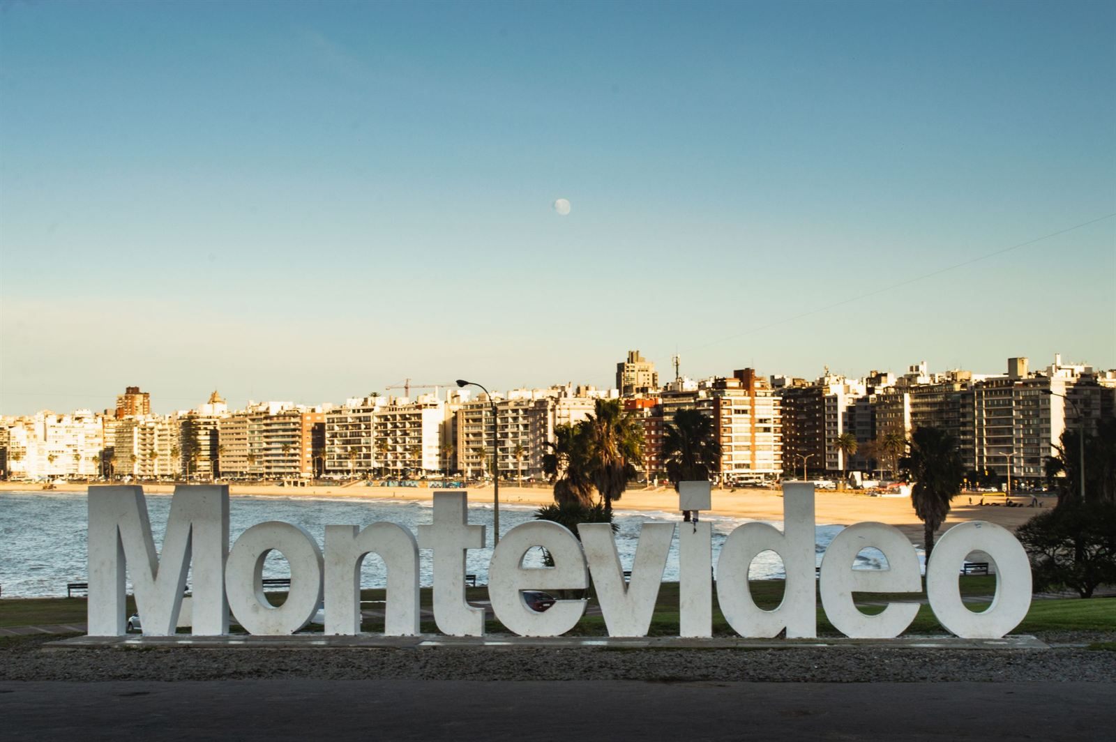 Large white Montevideo letters on the waterfront with apartment buildings along the beach behind